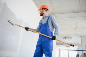 Painter in uniform paints the wall